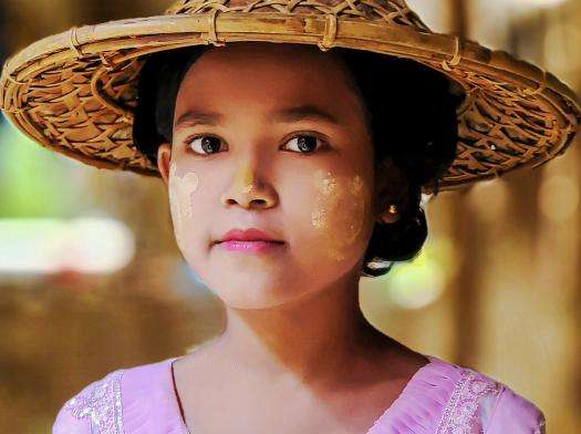 A Rohingya girl wearing face paint and a straw hat.