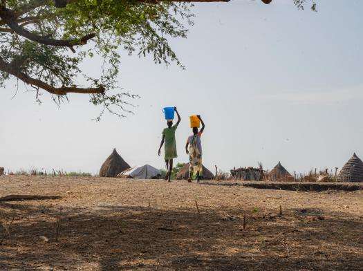 Two women carrying water on their heads from the river in Aree, village in South Sudan
