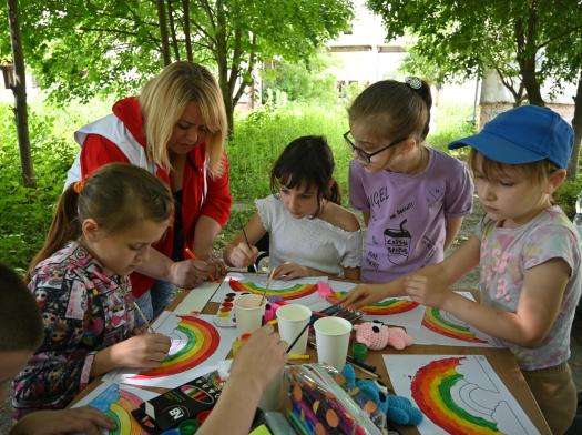 A group of children draw rainbows under the watch of an MSF psychologist during a therapy session in Ukraine