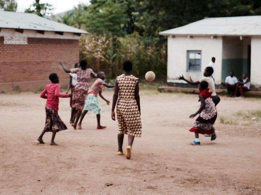 Girls playing a game outside with a ball. 