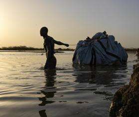 A man carries belongings through flood waters