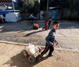 A Palestinian child fetches water from a distribution point in Rafah, Gaza.