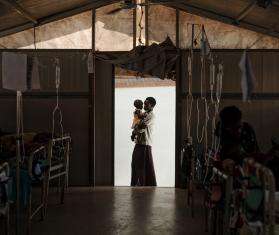 Silhouette of a mother holding a child in the door frame of an MSF hospital in South Sudan.