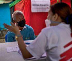 A patient sits at a table in front of an MSF staff member for a free X-ray at an MSF tuberculosis (TB) screening sites in Manila.