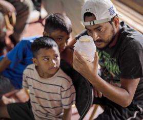 A man and boy look at a jar of mosquitoes to release as part of an MSF project to prevent dengue in Honduras