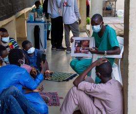 Several MSF medics sit on the floor in a circle in Nigeria where they work on the Kano project.