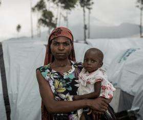 A woman holding a baby in a makeshift camp near Goma, Democratic Republic of Congo