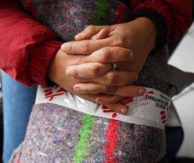A migrant woman's hands folded on her lap